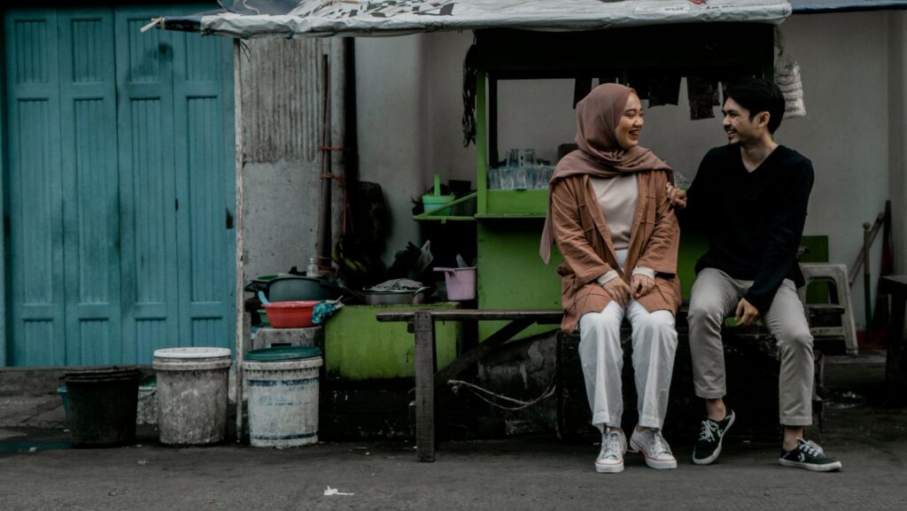 Pasangan muda tersenyum sambil berjalan bergandengan tangan, memperlihatkan tips cara pacaran yang menyenangkan